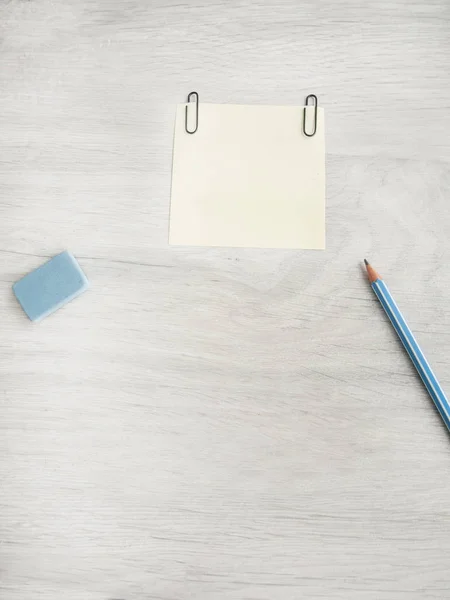 Mesa de oficina con accesorios: hoja en blanco, borrador, lápiz sobre una mesa gris de madera. Visualización desde arriba y copia de texto —  Fotos de Stock