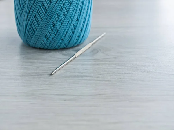 Všechno pro pletení: přadena z modrých nití a křivě na šedém dřevěném stole. Pohled shora. Kopírovat místo Close-up — Stock fotografie