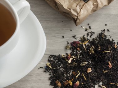 Çay kavramı. Ahşap gri bir masada beyaz fincan çay ve kuru çiçek çayı. Yukarıdan görüntüleyin. Close