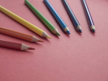 Kırmızı arka plan üzerine renkli kalemler. Üst te. Kopyalama alanı