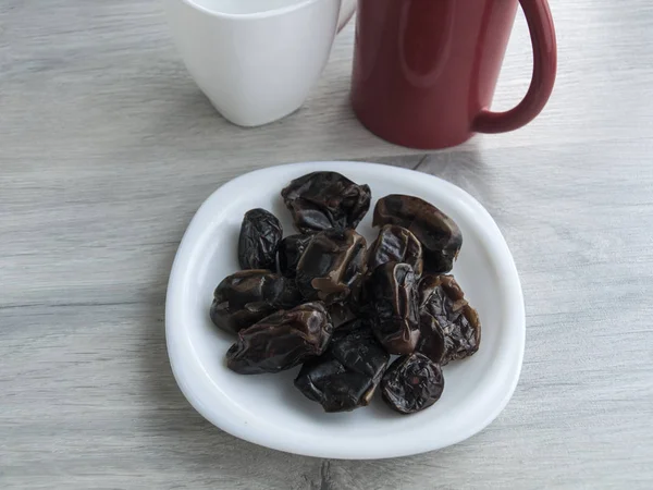 Healthy food: Dried dates on a saucer, red cup, white cup on a wooden gray table. Top view. Copy space