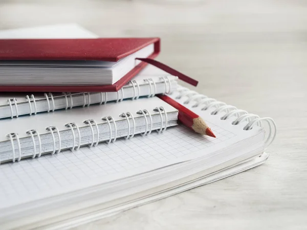 Accesorios de oficina: una libreta roja, una libreta blanca y un lápiz rojo sobre un escritorio gris de madera. De vuelta a la escuela. Perder el control. Vista superior. Copiar espacio — Foto de Stock