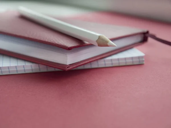 Akcesoria biurowe: biały Notatnik, czerwony Notatnik i biały ołówek na czerwonym tle. Edukacji. Biznesowych. Koncepcja. Widok z góry. Kopiuj przestrzeń — Zdjęcie stockowe