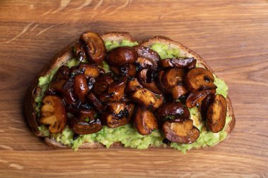 Kepekli tost püresi avokado ve bir kesme tahtası üzerinde ızgara mantar kadar Clise