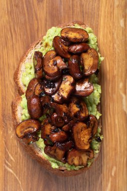 Kepekli tost püresi avokado ve bir kesme tahtası üzerinde ızgara mantar kadar Clise