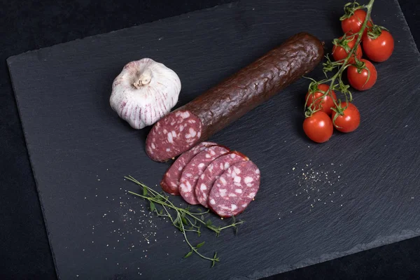 Smocked sausage on black stone plate — Stock Photo, Image