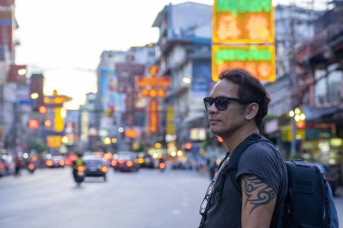 arka planda bulanık Çin kasabası ile Casual giysi ve güneş gözlüğü yarım vücut portre bir Asya Backpacker adam