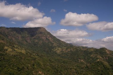 bulutlu mavi gökyüzü altında yeşil dağ aralığı
