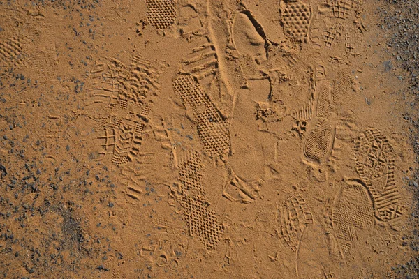 Textur der Schuhe Fußabdrücke auf goldenem Sand Hintergrund — Stockfoto