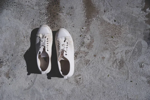 a pair of vintage white sneaker or shoes on cement ground floor