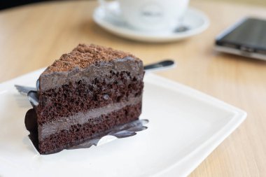 çikolatalı pasta dilimi, katman çikolata fudge beyaz tabakta, ahşap masa