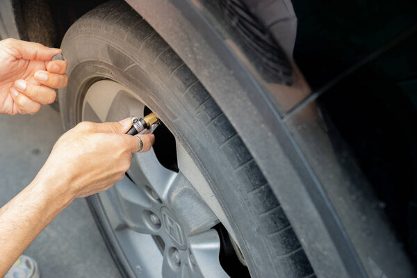 Man filling air in the tires of car. close up hand