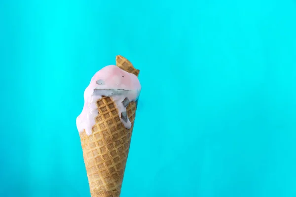 melted ice cream cone on mint blue background