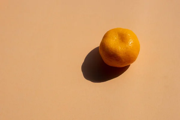 a whole oranges with strong shadow on orange background, copy space