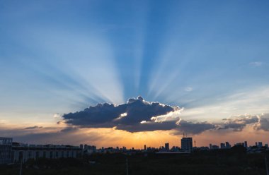 Sunbeam günbatımı süre içinde arka planda Bina silhueete ile dramatik bulut üzerinden