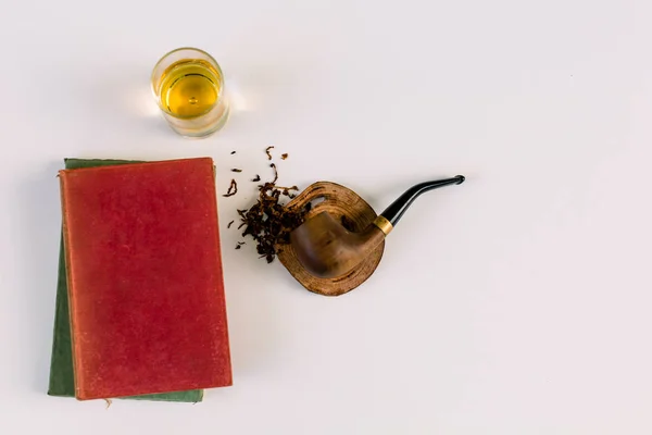 Tütün fleks Vintage tütün boru bundan bir bardak viski ile beyaz bir yüzeye dökülmesini bırakır ve yanına kitap 