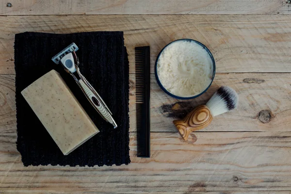 Flat lay of shaving and grooming items on a wooden surface