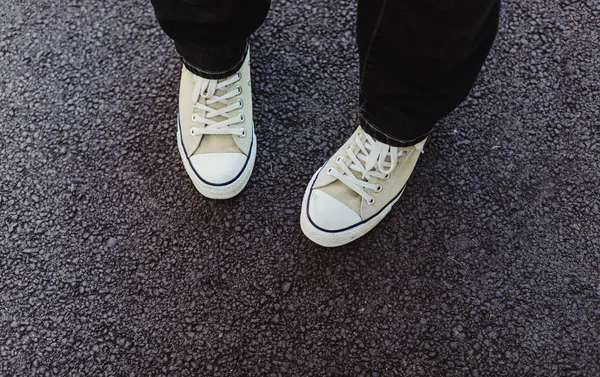 Asfalt üzerinde duran rahat spor ayakkabı giyen feet aşağı bakıyor 