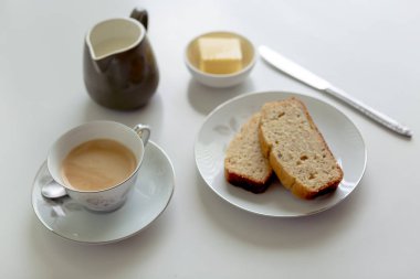 Çay muz ekmek tereyağı ve krem beyaz bir yüzeye sürahi ile