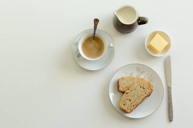 Çay muz ekmek tereyağı ve krem beyaz bir yüzeye sürahi ile