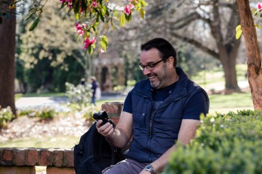 bir cep telefonu kullanarak bir parkta oturan 50 yaşındaki adam - gülümseyen