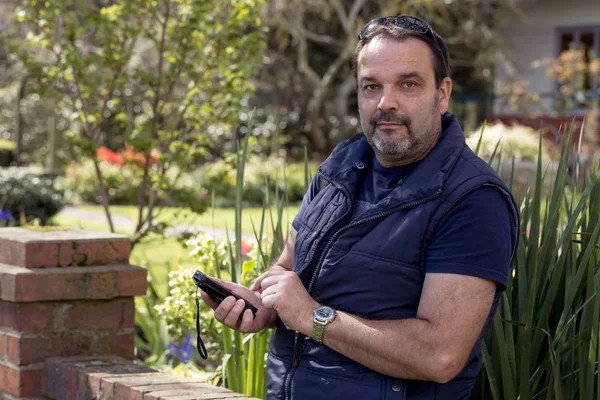 50 yaşındaki adam ile onun cep telefonu ararken bir park manifatura ayakta