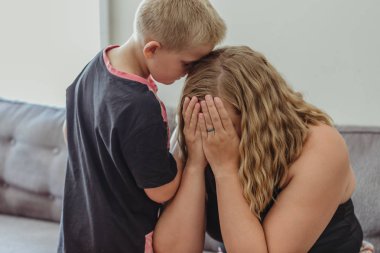 annesi için ilgili ve onun onun rahatlatıcı içine eğilerek genç çocuk ağlıyor