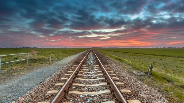 消失的铁路旅行到地平线下的蓝色和红色的天空作为一个概念的天堂和自由 — 图库照片
