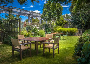MARLBOROUGH, NEW ZEALAND - DECEMBER 6: Home backyard with garden table set in sunny a lush garden with shade of trees on a summer day clipart