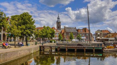 Blokzijl, Hollanda - 13 Temmuz 2017: Blokzijl tarihi köy eski düz dipli gemiler ve anıtsal ve kilise, Hollanda ile güneşli yaz gününde limanda