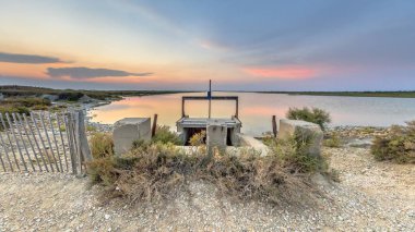 Hidrolik Weir, Camarque Bölgesel Doğa Koruma Alanı Provence Alpes Cote d 'Azur, Fransa' da güzel bir gün batımının altında renkli bir gölde barajda.