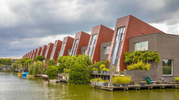 Экологические дома со встроенными солнечными панелями и висячими вертикальными садами на набережной в городской зоне Хаге, Нидерланды
