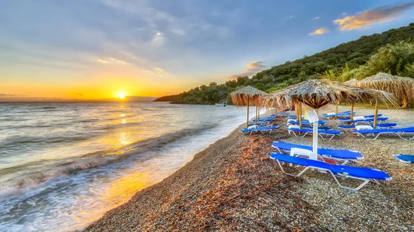 Gün batımında mavi plaj yataklar plajda Peloponnese, Yunanistan ile hasır şemsiyeler