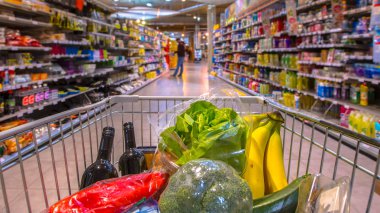 Süpermarketteki market arabası müşterilerin bakış açısından bakılan gıda ürünleriyle dolu.