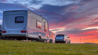 Güzel gün batımı altında çimenli bir kamp kamp karavan ve araba park