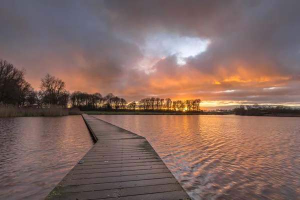 Holzsteg im See unter orangefarbenem Sonnenuntergang — Stockfoto