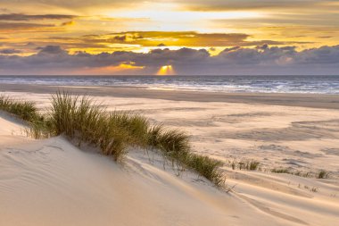Hollanda, Ameland adasından, Kuzey Denizi 'nde gün batımının üzerindeki kum tepesinden manzara
