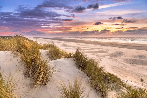 Hollanda, Ameland adasından, Kuzey Denizi 'nde gün batımının üzerindeki kum tepesinden manzara