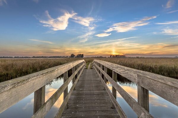 Wooden bridge for bicycles crossing river at sunset, Groningen, Netherlands