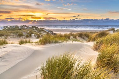 Hollanda, Ameland adasından, Kuzey Denizi 'nde gün batımının üzerindeki kum tepesinden manzara