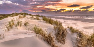 Hollanda, Ameland adasından, Kuzey Denizi 'nde gün batımının üzerindeki kum tepesinden manzara