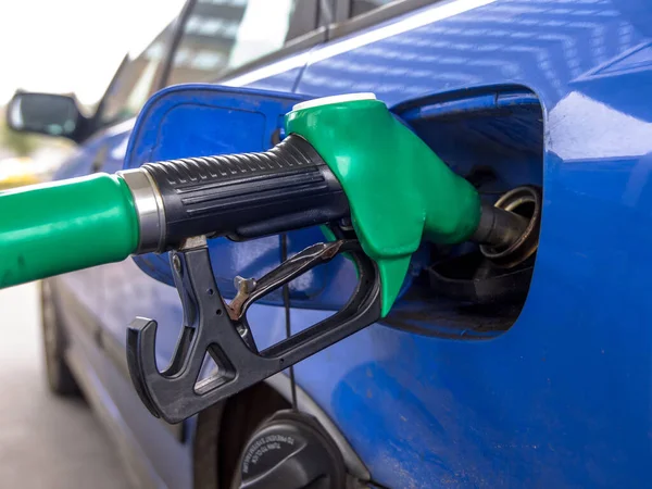 Mavi araba benzin istasyonunda yakıt ikmali yapıyor. Elektrikli araçların bu çağında daha nadir görüldüğü tahmin edilen bir sahne
