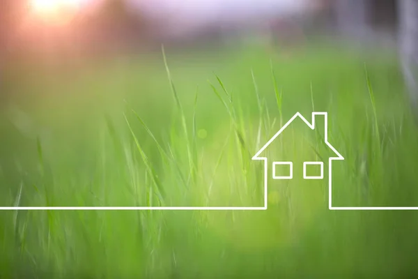 Conceptual green eco house icon on blurred grass copy space background