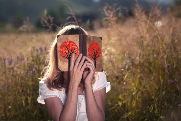 Woman with love book in the sunny meadow.