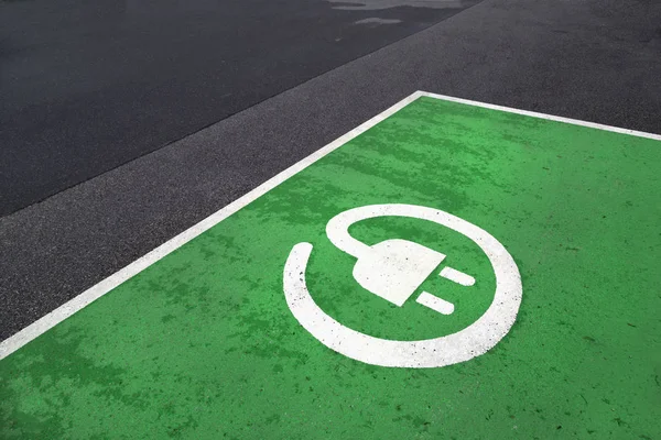 Free green colored electric vehicle parking station painted on asphalt floor.