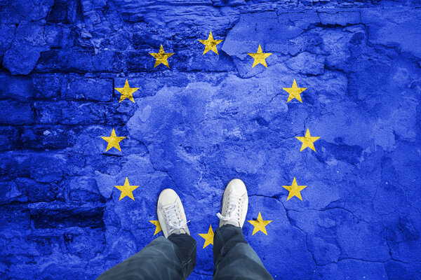 Top view of a man standing on damaged aged city floor with painted European Union flag. Point of view perspective used. Conceptual EU disintegration background.