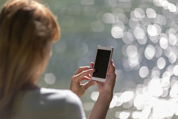 Close up of a blonde woman hands typing on his smart phone. Selective focus used.