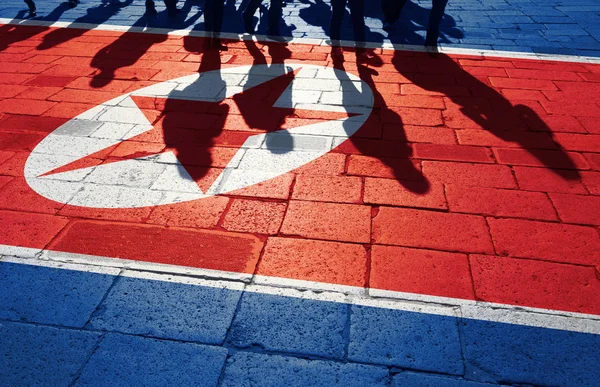 一群人在街上走着 地板上挂着画着朝鲜国旗 概念政治关系与邻居 免版税图库图片