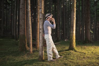 Ormanda şapkalı adam bir elma yemek ve günbatımı keyfini çıkarın.