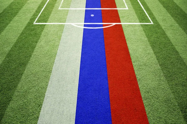 Empty soccer field with ground lines on sunny grass texture with painted Russia flag. Goal side perspective used.